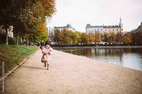 2 year old girl running on the side of the lakes in Oesterbro Copenhagen on a beautiful fall day