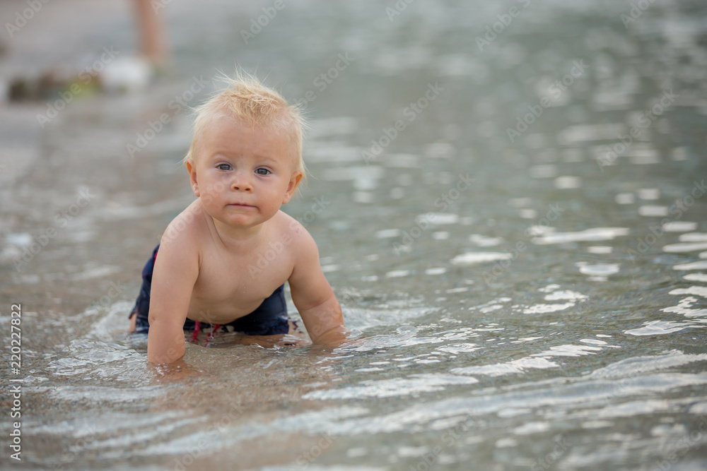 Toddler baby boy, child playing in the water at the beach Toddler baby boy, child playing in the water at the beach