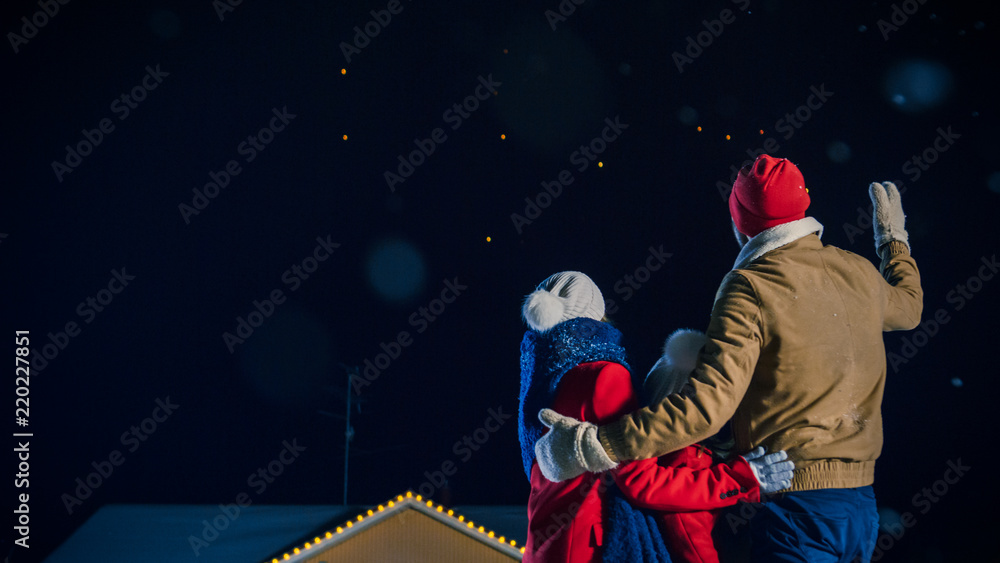 Happy New Year Celebration, Young Family of Three Standing in the Front Yard Watching Beautiful Fireworks. In the Evening while Snow is Falling Father, Mother and Cute Little Daughter Look up. Happy New Year Celebration, Young Family of Three Standing in the Front Yard Watching Beautiful Fireworks. In the Evening while Snow is Falling Father, Mother and Cute Little Daughter Look up.