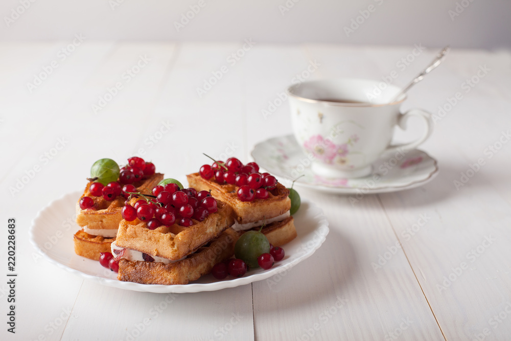 Viennese waffles with berries and a cup of tea stand on the table
