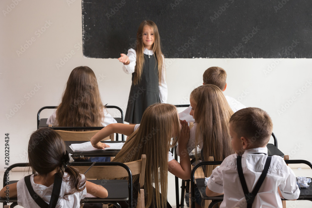 Obraz premium School children in classroom at lesson. The little boys and girls sitting at desks. Back to school, education, classroom, lesson, learn, lifestyle, childhood concept