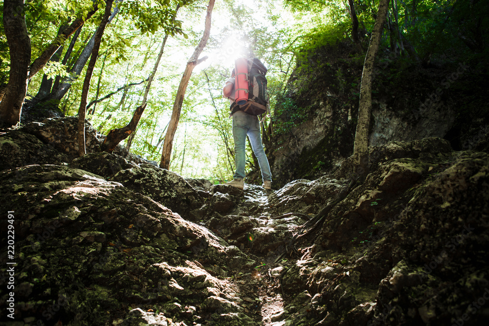 Fototapeta premium A man with a backpack and a karemate goes on a trek through the rocky gorge. Space for text.