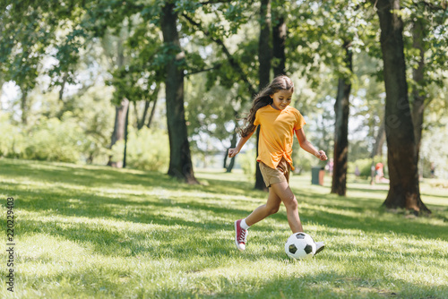 beautiful happy child playing with soccer ball in park