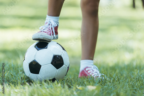 cropped shot of child standing with soccer ball on grass © LIGHTFIELD STUDIOS