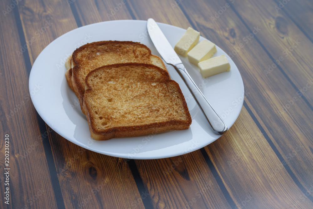 bread toast and several slices of butter on a plate on a wooden background bread toast and several slices of butter on a plate on a wooden background