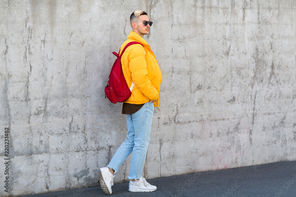 fashion guy standing near a concrete wall in yellow clothes fashion guy standing near a concrete wall in yellow clothes
