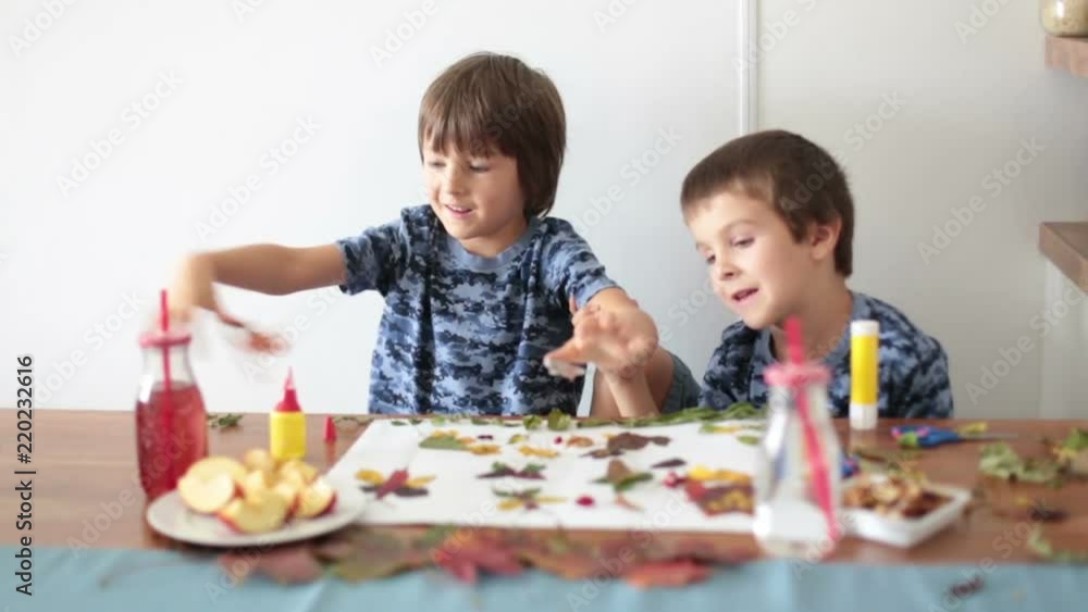 Sweet children, boys, applying leaves using glue while doing arts and crafts in school, autumn time Sweet children, boys, applying leaves using glue while doing arts and crafts in school, autumn time