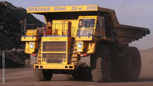 Dump truck. Mining truck. A giant truck rides on a technological road close-up. Dust from under the wheels. photo