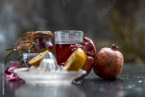 Close up of herbal face pack of pomegranate and lemon juice with rose water on wooden surface with some sliced lemons and pomegranates used for Dull skin. photo