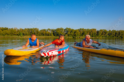 Joyful friends, a SUP surfers relax on the big river