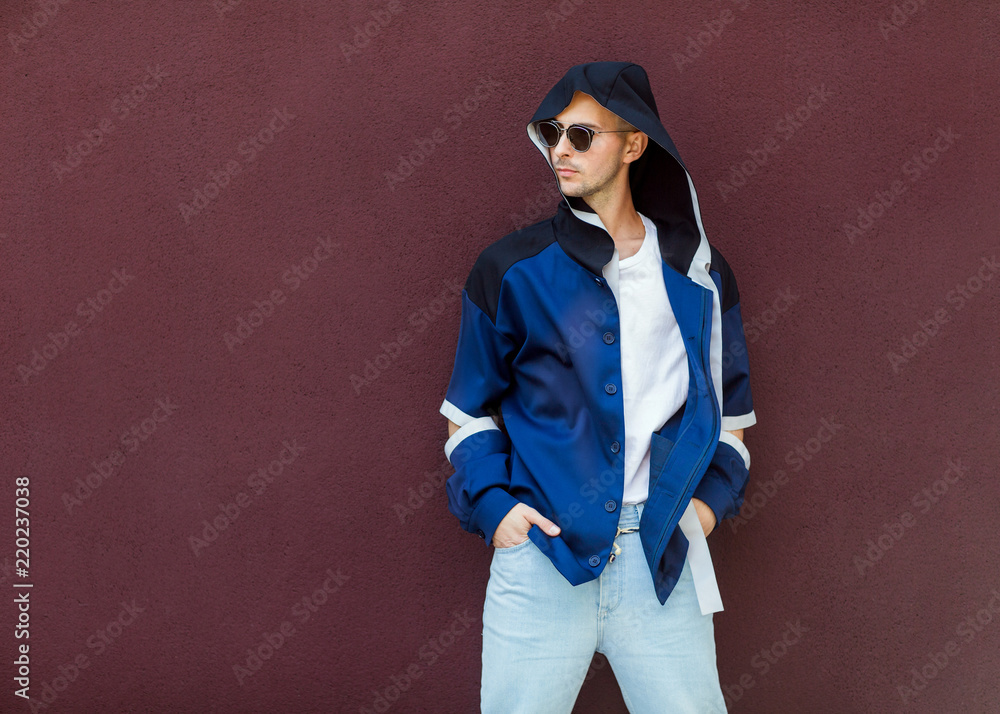fashion guy standing near a viola wall in blue clothes fashion guy standing near a viola wall in blue clothes