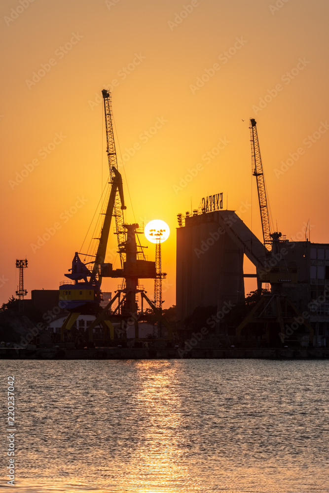 Port with cranes at sunset. 