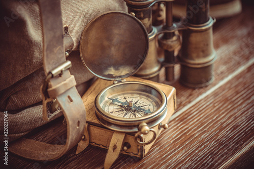 Old vintage compass, binoculars, and backpack. Travel navigation concept.