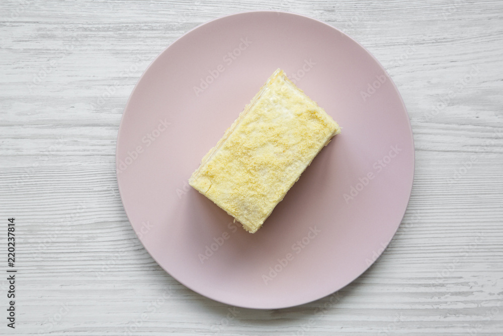 Piece of Napoleon Cake on pink plate over white wooden background, top view. Flat lay, from above, overhead.