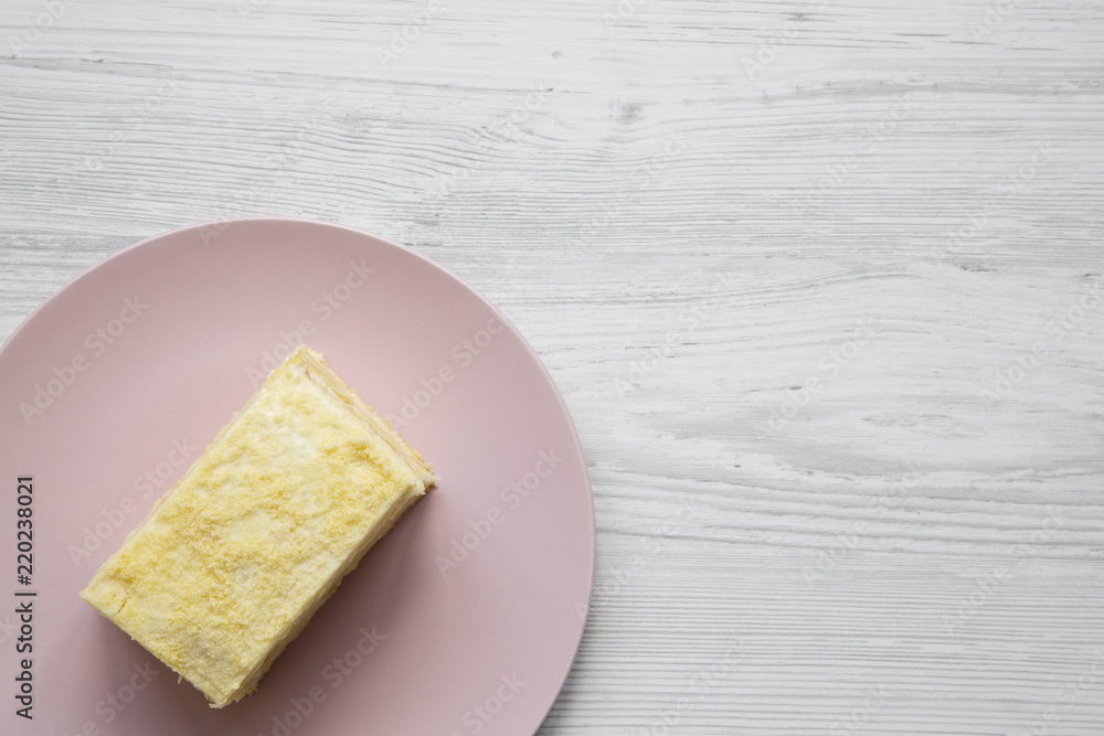 Piece of Napoleon Cake on pink plate over white wooden surface, top view. Copy space. Piece of Napoleon Cake on pink plate over white wooden surface, top view. Copy space.