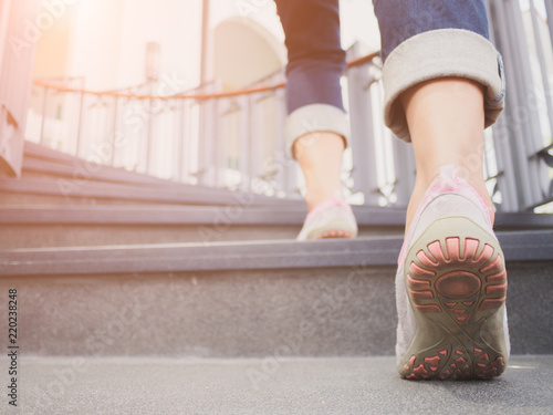 Fototapeta Młoda dorosła kobieta chodzi w górę schodków z słońcem bawi się tło.