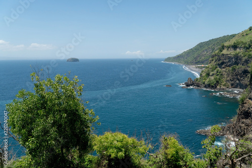Rocky coast with high cliffs, sea coast, ocean, mountains, sea, beach, sky, clouds. Bali, sea surf with breaking waves on the coast, Indonesia. Ocean with waves and rocky cliff.