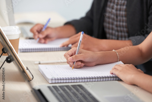 Cropped image of students writing essay or assignment photo
