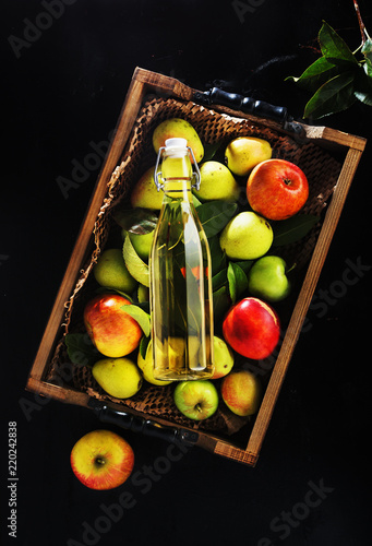 Apple cider vinegar and  apples on black wooden background.