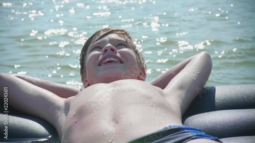 A young guy is swimming in the sea on an inflatable mattress. Positive emotions. Hot summer day