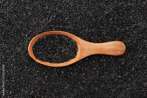 Black sesame seeds on wooden spoon background texture pattern