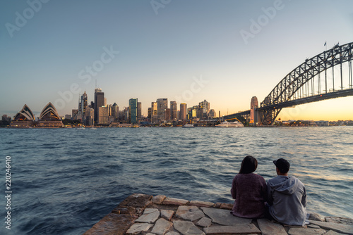 Romantic couple looks at Sydney skyline at dusk in Sydney New South Wales, Australia.