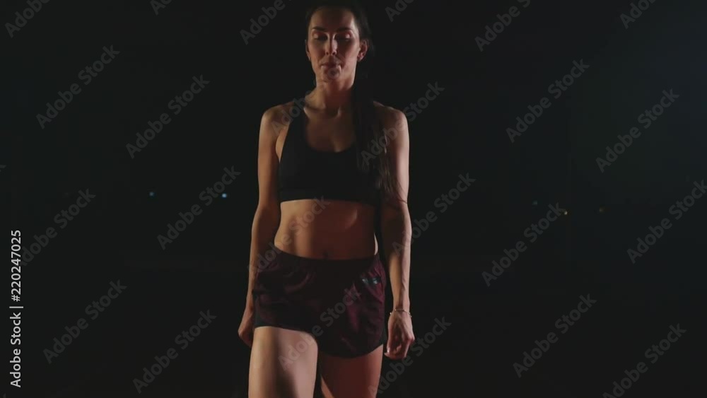 Athlete woman in black shorts and a t-shirt in sneakers are in the running pads on the track of the sports complex and run in slow motion Athlete woman in black shorts and a t-shirt in sneakers are in the running pads on the track of the sports complex and run in slow motion