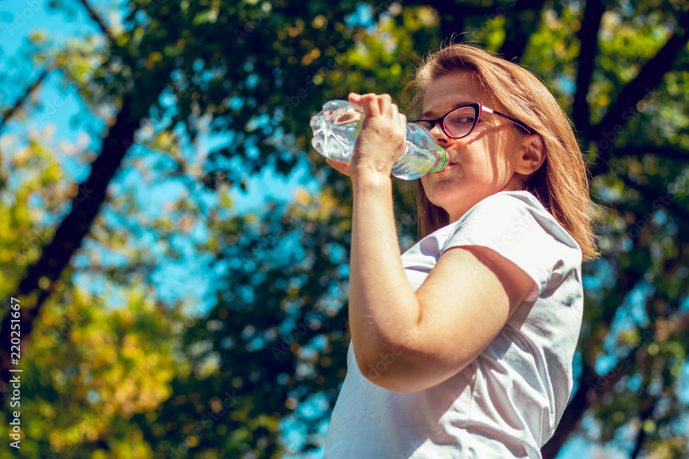 Girl looking in the camera while drinking water from a bottle Girl looking in the camera while drinking water from a bottle