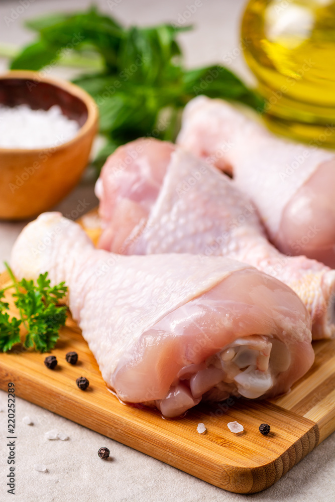 Raw chicken legs with spices and herbs on cutting board Raw chicken legs with spices and herbs on cutting board