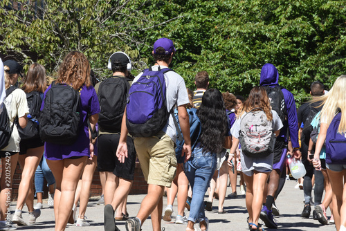 A group of students walk to class through campus at ECU