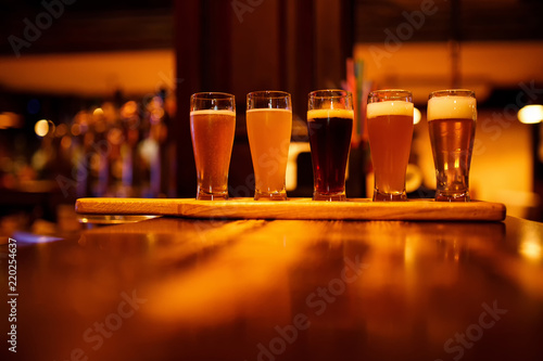 Various types of craft beer in small glasses on a wooden table in a pub. photo