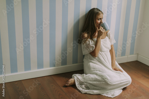 Young pregnant woman sitting by the wall