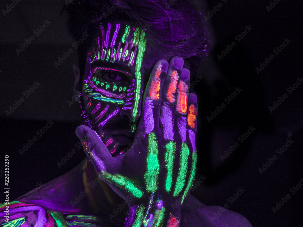 Handsome guy with UV body art close his face Stock Photo by