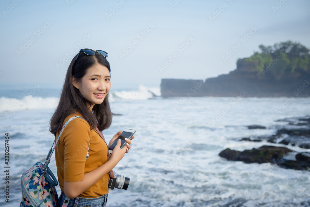 Traveler photography girl with dslr camera take photo with Bali beach at background. Young lady professional photographer. Asian hipster female traveling concept
