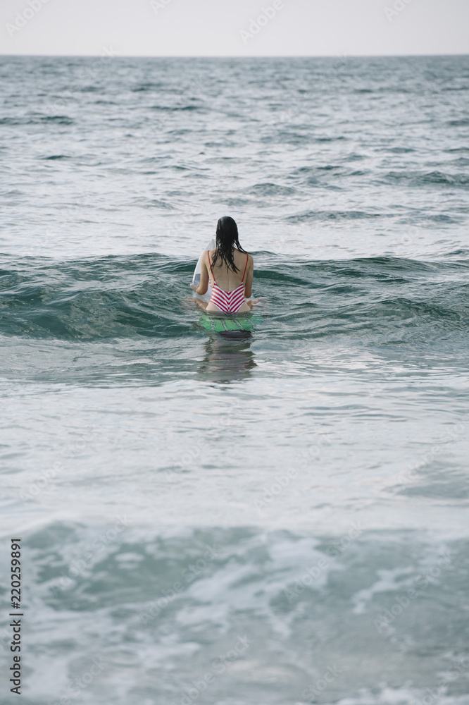 Young woman surfing the wave on his surfboard