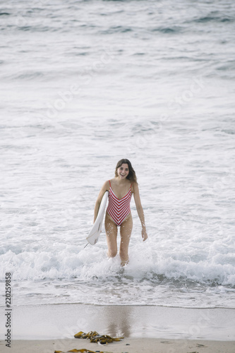 Portrait of a surfer woman on a beach holding a surfboard