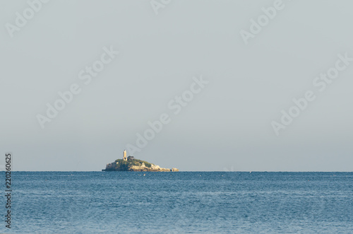 Tropical island on open sea with light tower