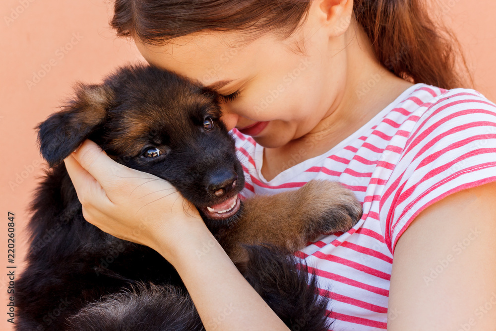 Obraz premium Young woman enjoys hugging a small cute puppy