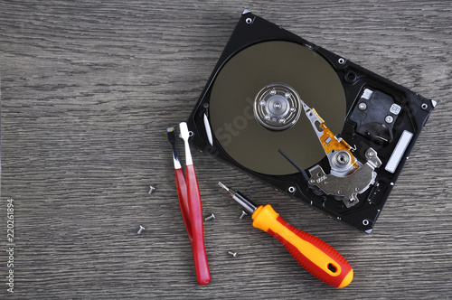 Hard drive and repair tool on wooden table close up 