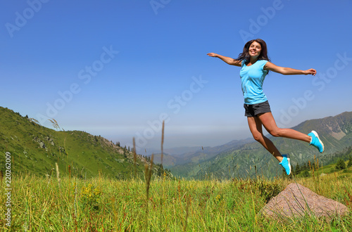Happy young woman jumping against mountains