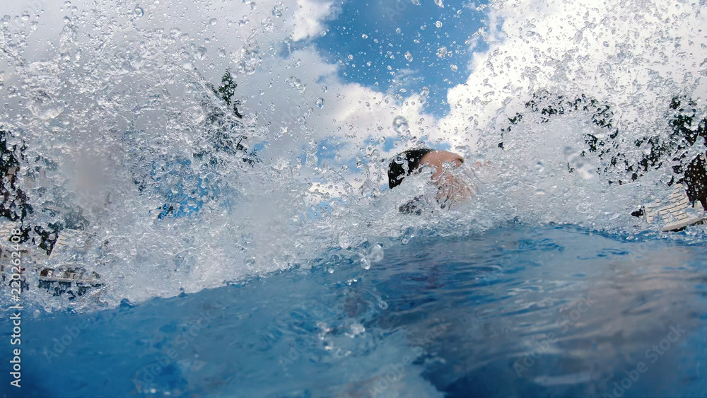 Teen girl in bikini slides down a plastic slide and splashing in swimming pool