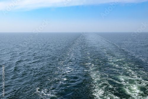 Trail in the sea from cruise ship. Enless ocean and horizon. Background with copy space for text.