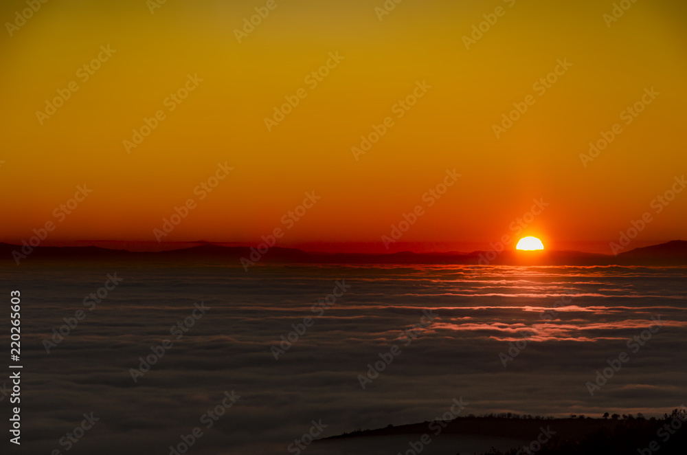 Mountain range summits with visible silhouettes through the morning sunrise colorful fog