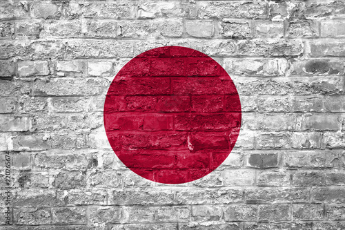 Flag of Japan over an old brick wall background, surface