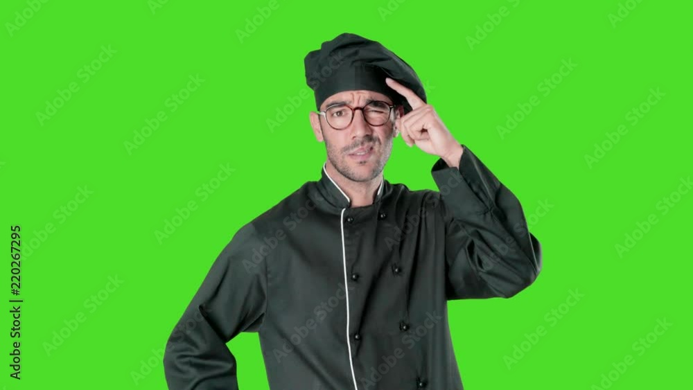 Puzzled young chef posing against green background Puzzled young chef posing against green background