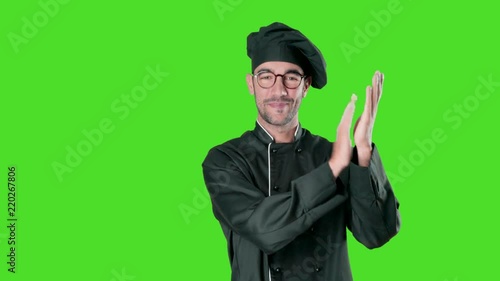 Happy young chef applauding against green background