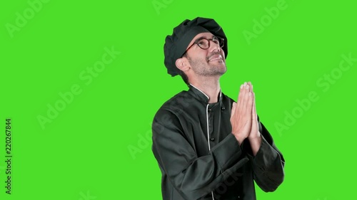 Hopeful young chef praying against green background