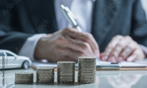 Car insurance and car service. Businesswoman with stack of coins and toy car, business and financial concept.