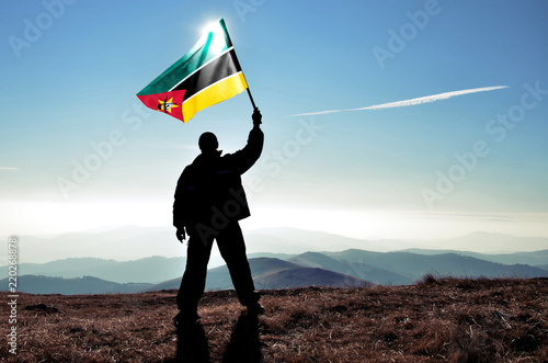 Vászonkép Successful silhouette man winner waving Mozambique flag on top of the mountain p