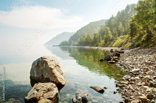 Fotografie Landscape of the shore of the lake with rocks and mountains in the background